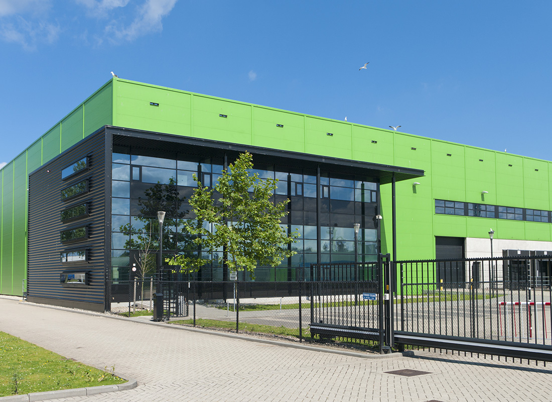 Business Insurance - Green and Black Warehouse Building With a Black Fence on a Sunny Day